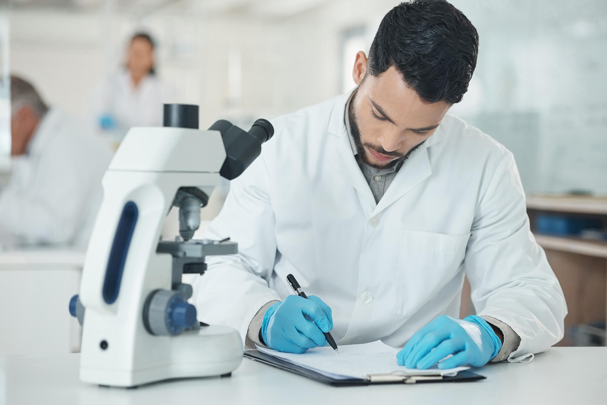 Scientist taking notes next to a microscope